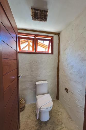 a bathroom with a toilet and a window at Casa Caroá - Chalé 1 in Japaratinga