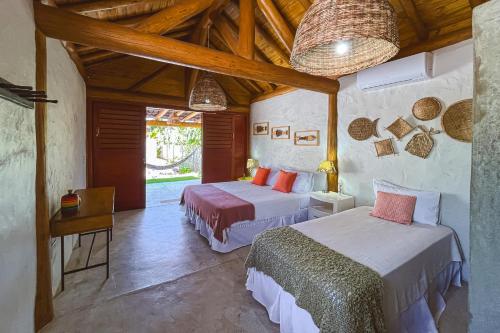 two beds in a room with wooden ceilings at Casa Caroá - Chalé 1 in Japaratinga