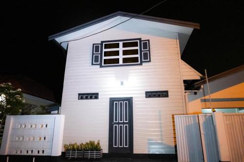 una pequeña casa blanca con una puerta y ventanas negras en Rena’s Appartement, en Paramaribo