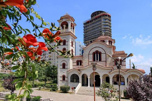 an old building with a tall building in the background at NOVA Sea View Apartments in Durrës