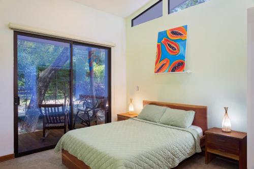 Schlafzimmer mit einem Bett und einer Glasschiebetür in der Unterkunft Casa Papaya - Eco Casita Phase 1-1 in Iguana