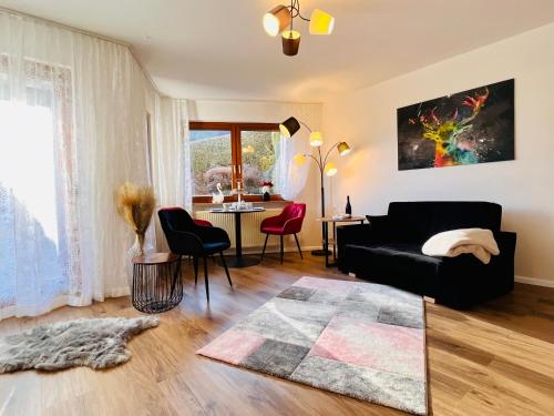 ein Wohnzimmer mit einem schwarzen Sofa und einem Tisch in der Unterkunft Boutique Apartment in Lenzkirch