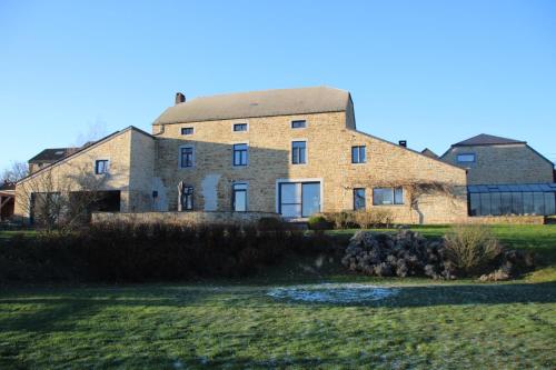 a large brick building in a field with a yard at Prim'tout in Ohey