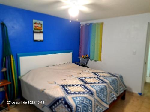una camera con un letto con una parete blu di Confortable y colorida casa con piscina a Cancún