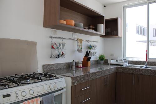 a kitchen with a stove and a sink at CasaMuyuyo - Hermosa Casa de Playa a 1h20 de Guayaquil in Playas