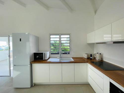 a white kitchen with a sink and a refrigerator at Emeraude Bay, Magnifique T3 vue mer, proche plage in Le Gosier