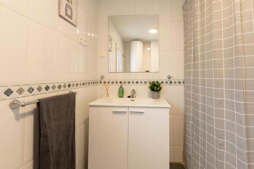 a white bathroom with a sink and a mirror at Casa DAURO in Granada