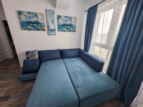 a blue couch in a living room with a window at Black Sea Overlook in Mamaia Sat/Năvodari