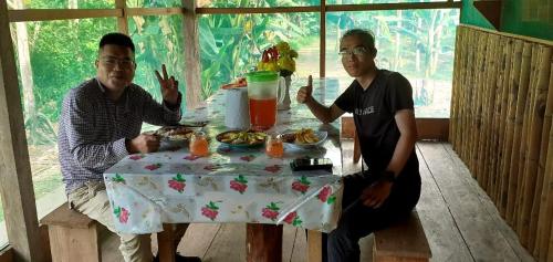 twee mannen aan een tafel met eten bij Refugio Rural Amazonas in Iquitos