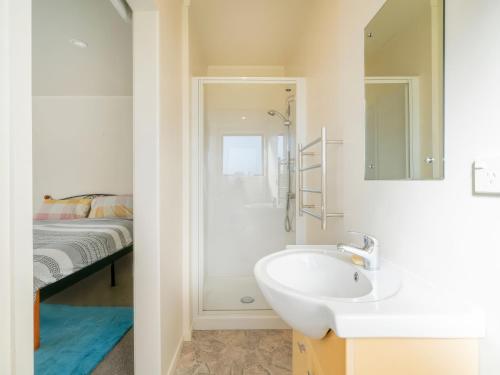 a bathroom with a sink and a shower with a bed at Hosts on the Coast - Seas the Day in Cooks Beach