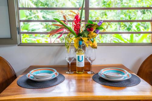 a table with two plates and a vase with flowers at Casitas Del Rio Riverfront Nature Lodge in Uvita