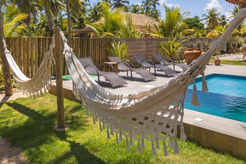 a hammock in a yard next to a swimming pool at Casa Caroá - Chalé 1 in Japaratinga