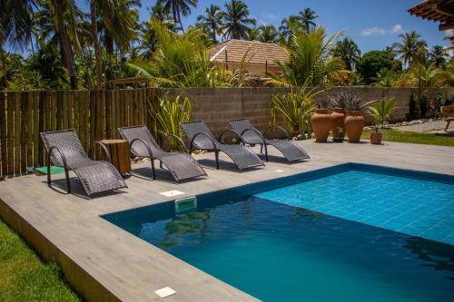 a group of chairs and a swimming pool at Casa Caroá - Chalé 1 in Japaratinga