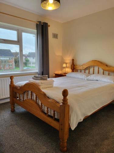 Un dormitorio con una gran cama de madera y una ventana en Greenview, en Ballysheedy