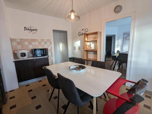 una cucina e una sala da pranzo con tavolo e sedie bianchi di Grande maison avec extérieur, jacuzzi et billard a Vierzon
