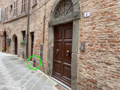 a brown door with a green circle next to a building at 2 King Bed, 2 Full Bathroom Apartment in Umbria - Tuscany in Città della Pieve