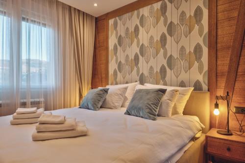a bedroom with a white bed with towels on it at Bjelasica 1973-Modern Mountain 2 in Kolašin