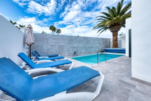 a pool with blue chairs and a palm tree at Casa Eva - Private Pool, BBQ & Free Parking By Lanzarote Vacation Homes in Los Pocillos