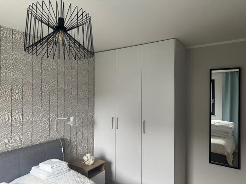 a bedroom with a white cabinet and a mirror at Apartament w Nautikka Resort Krynica Morska in Krynica Morska