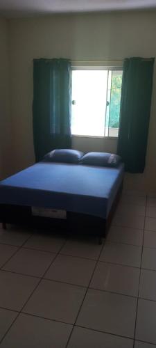a bed sitting in a room with a window at Apartamento da lília in Alto Caparao