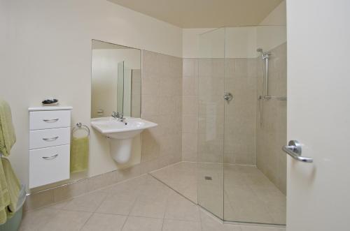 a white bathroom with a sink and a shower at Pavilion Beachfront Apartments in Mount Maunganui