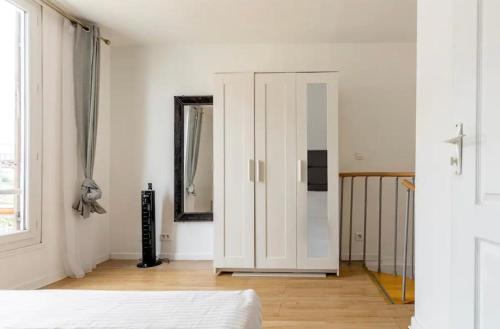 een slaapkamer met witte muren en een bed en een spiegel bij Le Gandhy 2 in Le Blanc-Mesnil