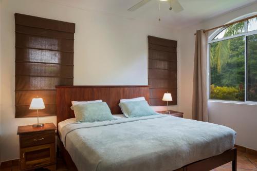 a bedroom with a bed with two lamps and a window at Villas Iguana A-13 Beachfront Condo in Iguana