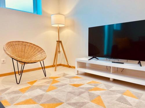 a living room with a flat screen tv and a chair at Penagoda Beach House in Espinho
