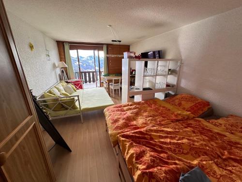 1 dormitorio con 1 cama y 1 silla en "Le Ptit Nid" studio avec vue à couper le souffle à Leysin !, en Leysin