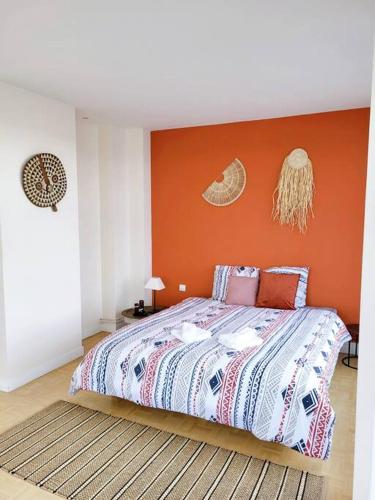 a bedroom with a bed with an orange wall at Penthouse/ Rooftop Ocean view in Le Havre