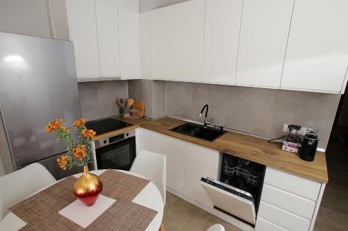 a kitchen with white cabinets and a table with a vase on it at NOVA Sea View Apartments in Durrës