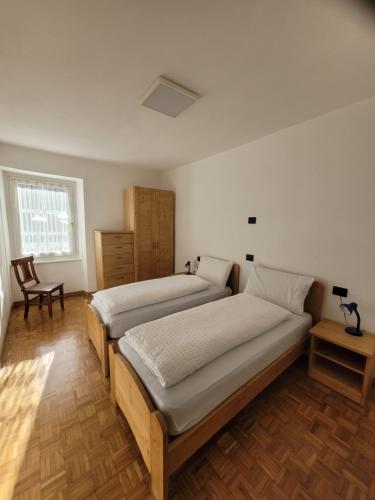 een slaapkamer met 2 bedden en een stoel bij Casa Pontesana in Pellizzano