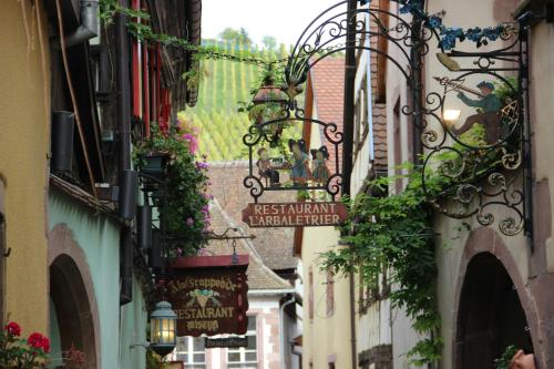 a narrow street with a sign on a building at Villa Maeva - Parking, Sauna & Fitness in Riquewihr
