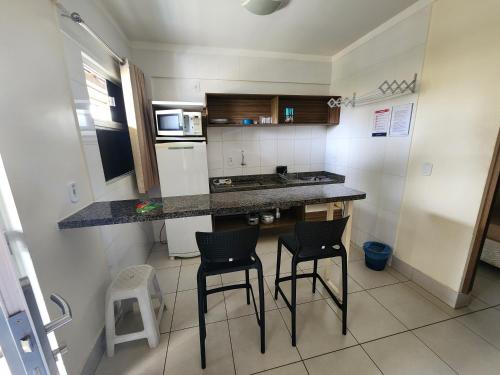 a kitchen with two bar stools and a counter top at Lacqua diRoma 1 - Apartamentos JN in Caldas Novas