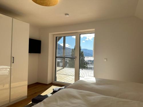 - une chambre avec un lit et une vue sur un balcon dans l'établissement Das Lungau View - NEUERÖFFNUNG, à Mauterndorf