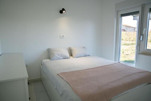 a bed in a white room with a window at Lucas apartment in Čapljina
