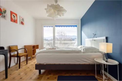a bedroom with a bed and a large window at Logement Autour de Moi * * * * * in Chambéry