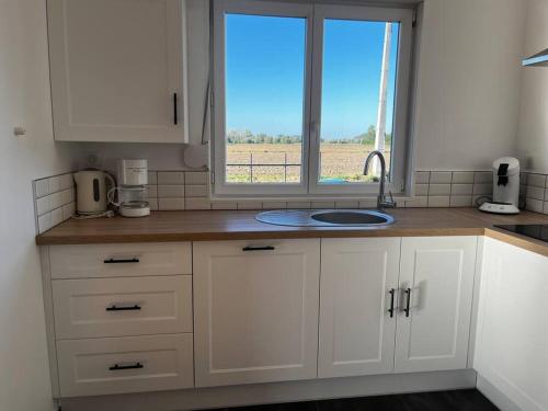 a kitchen with white cabinets and a window and a sink at Gîte L’Erable in Haverskerque