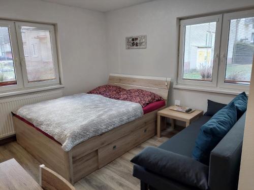 a bedroom with a bed and a couch and windows at BIKE apartments 2 in Hodruša