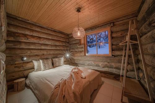 a bedroom with a bed in a log cabin at Koto Lodge - Yllästunturi in Äkäslompolo