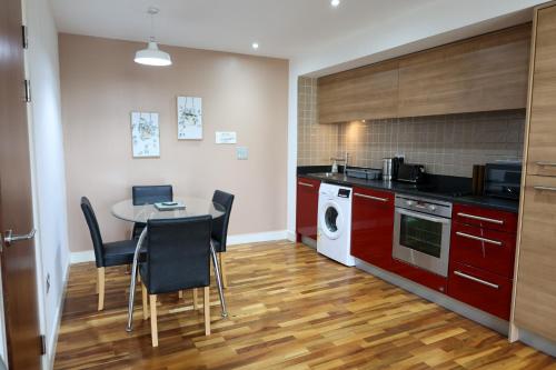 a kitchen with red cabinets and a table with chairs at Centrally located 1BR Apt near Edg Cricket, University of Bham, Priory Hospital & Cannon Hill Park in Birmingham