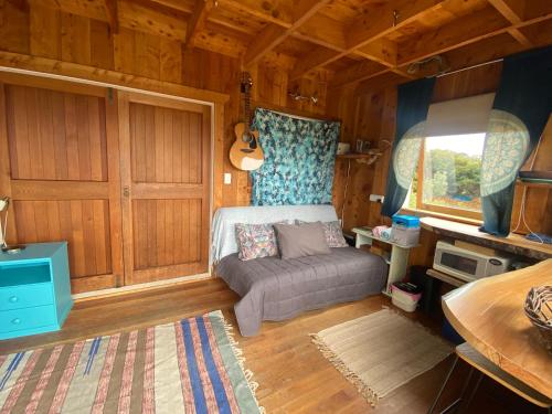 Palm BeachにあるKereru Cabinの木製の部屋にベッド1台が備わるベッドルーム1室があります。