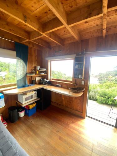 a kitchen with wooden floors and a large window at Kereru Cabin in Palm Beach