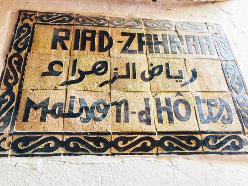 un panneau sur le côté d'un bâtiment avec écriture dans l'établissement Riad Zahraa Al Ismailia, à Meknès
