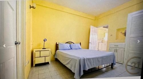 a bedroom with a bed and a yellow wall at Patrickville in Gwa Kay