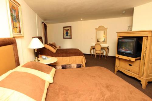 a hotel room with two beds and a television at Hotel Martell in San Pedro Sula