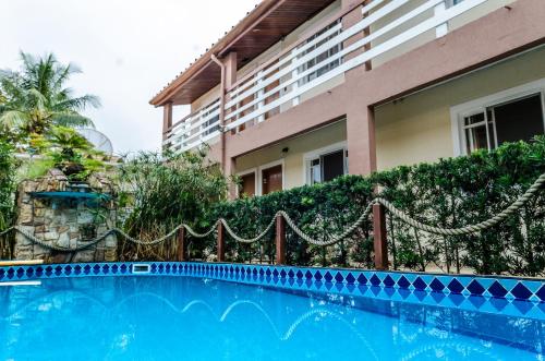 a swimming pool in front of a building at Pousada Vila da Praia in Bertioga