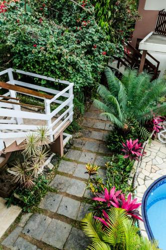 a garden with a white fence and some plants at Pousada Vila da Praia in Bertioga