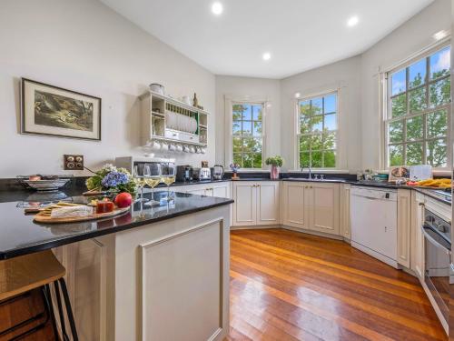a large kitchen with white cabinets and wooden floors at The Folly in Bilpin