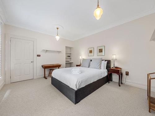 a white bedroom with a bed and two tables at The Folly in Bilpin